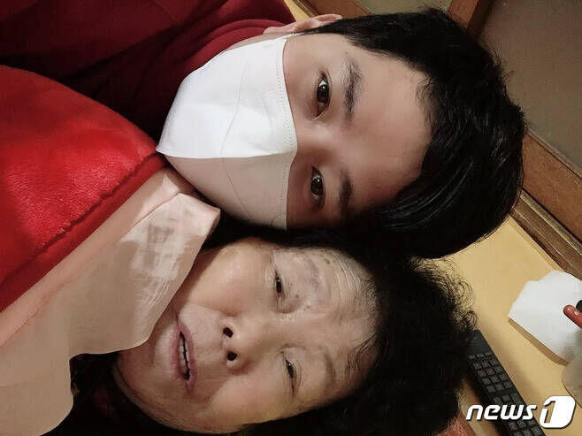 신종 코로나바이러스 감염증(코로나19)으로 병원에 입원한 할머니를 살리기 위해 방호복을 입고 할머니를 극진히 돌본 손자 박용하씨가 16일 완치돼 집으로 돌아온 할머니와 사진을 찍었다(박용하씨제공)2020.3.16/.&copy; 뉴스1