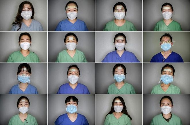 a group of people posing for a photo: The pads, plasters and tape protect the nurses' faces from painful sores that can develop as they tend to coronavirus patients for hours on end